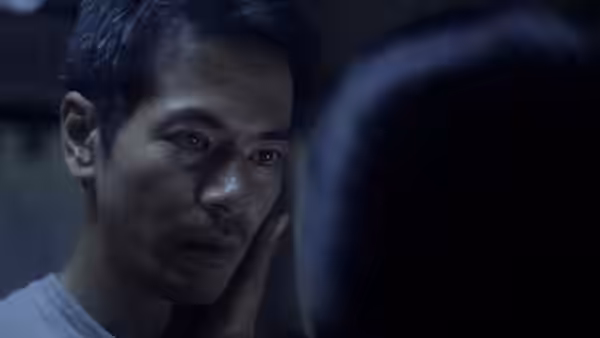 Oscar Ramirez (Jake Macapagal) gently touches a woman's cheek in a dim room