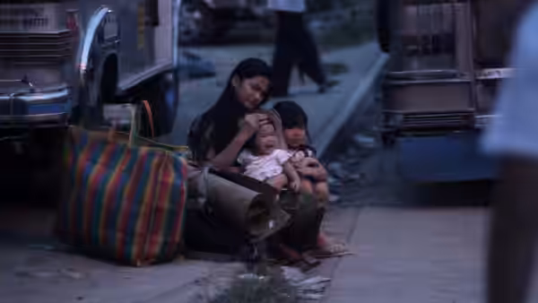 Mai Ramirez (Althea Vega) sits with her children beside luggage on a crowded city street