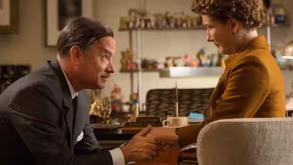 Walt Disney (Tom Hanks) leans forward and holds P.L. Travers's (Emma Thompson) hands in her office