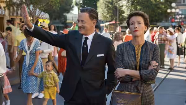 Walt Disney (Tom Hanks) waves to passersby as P.L. Travers (Emma Thompson) stands beside him