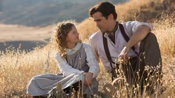Young Ginty (Annie Rose Buckley) sits in a field beside her father, Travers Robert Goff (Colin Farrell)