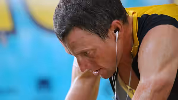 Lance Armstrong (Lance Armstrong) leans forward in a yellow cycling jersey, wearing earbuds