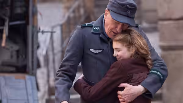 Hans Hubermann (Geoffrey Rush), in uniform, hugs Liesel Meminger (Sophie Nélisse) outdoors
