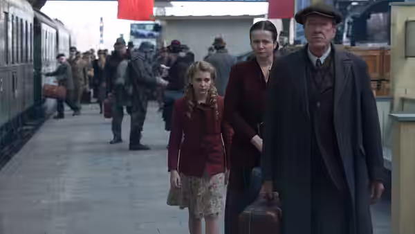 Liesel Meminger (Sophie Nélisse), Rosa and Hans Hubermann wait with luggage on a railway platform