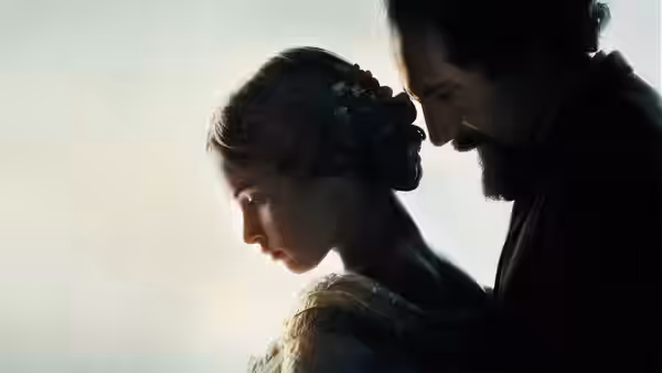 Charles Dickens (Ralph Fiennes) leans close behind Nelly Ternan (Felicity Jones) by a window