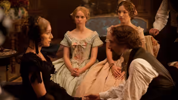 Charles Dickens sits beside Catherine Dickens and two young women in a richly furnished room