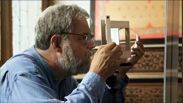 Tim Jenison peers through an optical device toward a painted interior