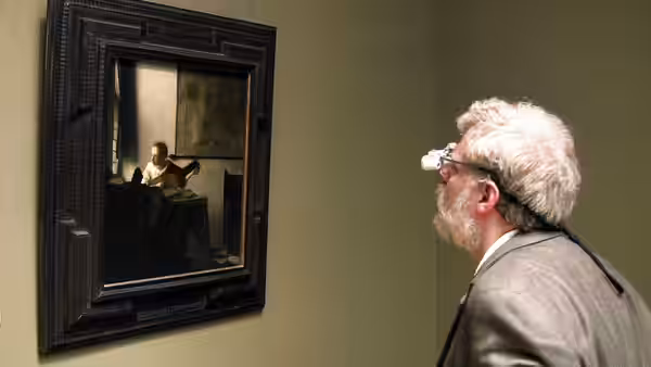 Tim Jenison examines a framed painting through a head-mounted optical device
