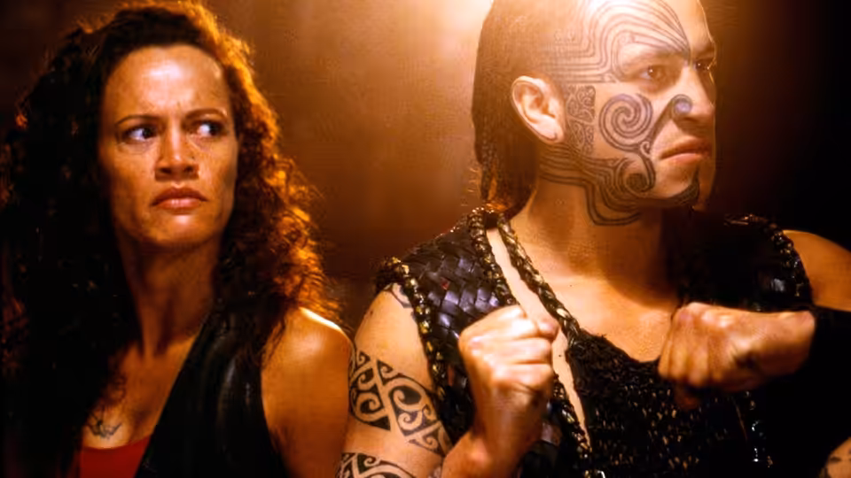 Beth Heke (Rena Owen) stands beside Jake Heke (Temuera Morrison) with clenched fists