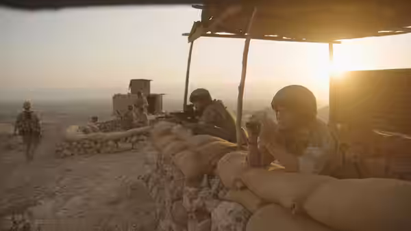 Soldiers take cover behind sandbags at a desert outpost
