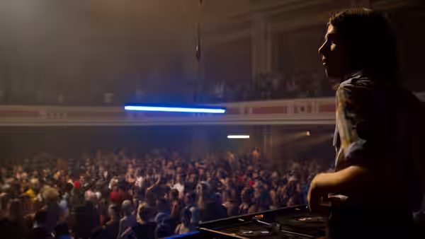 A DJ works the decks as a packed audience watches from the floor and balcony