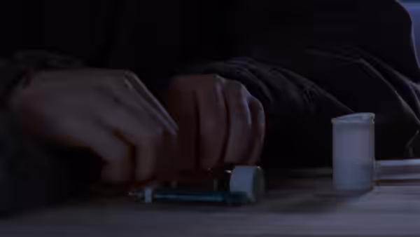 Hands preparing a syringe and small bottle on a wooden table