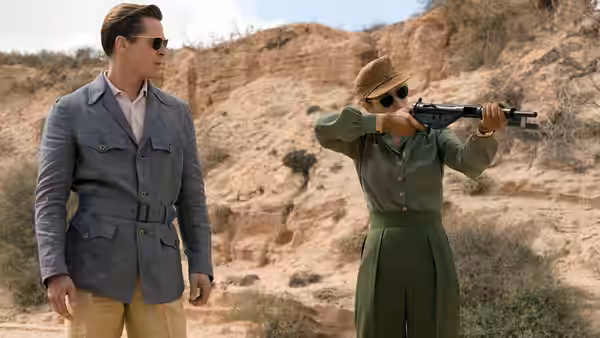 Max Vatan (Brad Pitt) watches Marianne Beauséjour (Marion Cotillard) aim a rifle in the desert