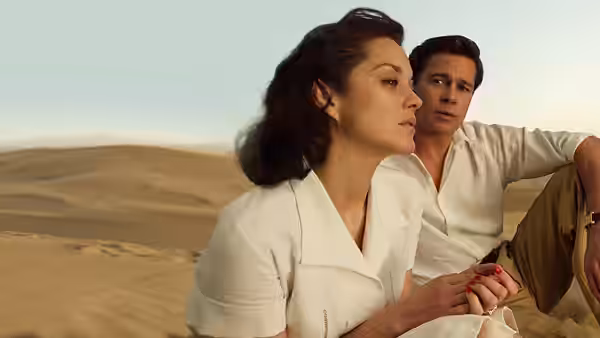 Marianne Beauséjour (Marion Cotillard) sits beside Max Vatan (Brad Pitt) among the desert dunes