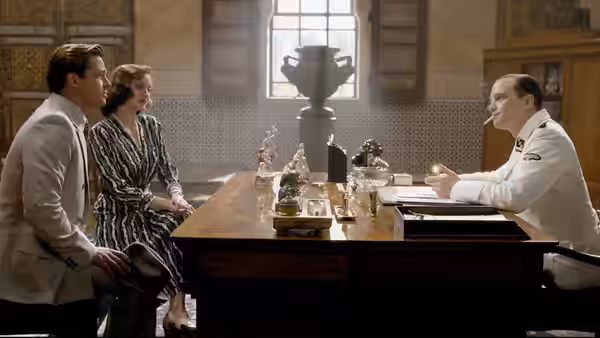 Max Vatan (Brad Pitt) and Marianne Beauséjour (Marion Cotillard) sit across a table from a uniformed man