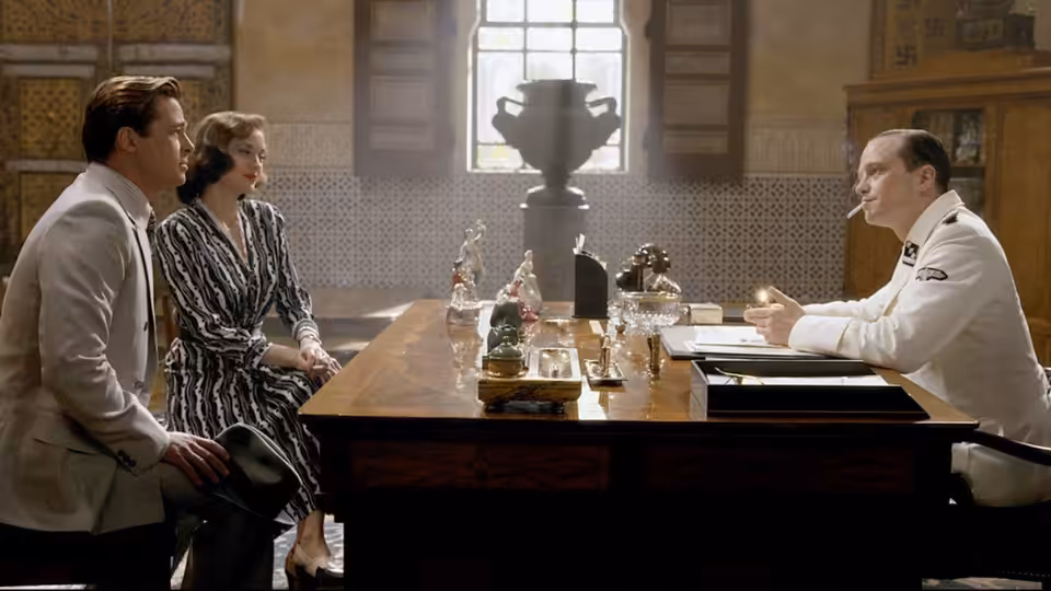 Max Vatan (Brad Pitt) and Marianne Beauséjour (Marion Cotillard) sit across a table from a uniformed man