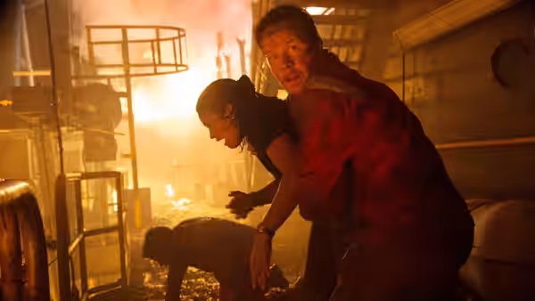 Mike Williams (Mark Wahlberg) helps a colleague through a firelit corridor aboard the rig