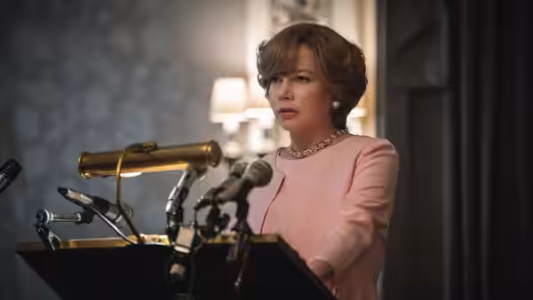 Gail Harris (Michelle Williams) addresses reporters from behind a bank of microphones