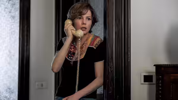Gail Harris (Michelle Williams) speaks on a telephone in a doorway