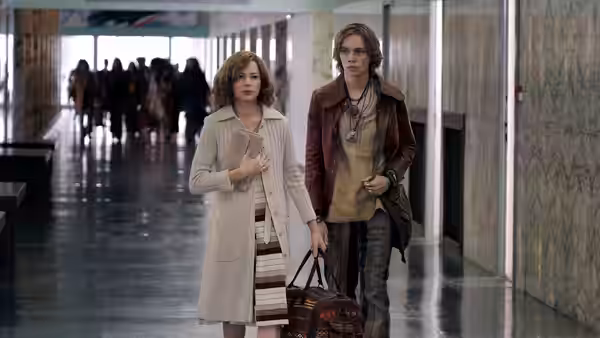 Gail Harris (Michelle Williams) walks beside John Paul Getty III (Charlie Plummer) through a corridor