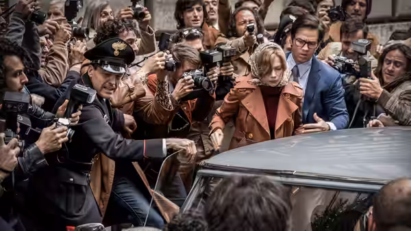 Gail Harris (Michelle Williams) and Fletcher Chase (Mark Wahlberg) push through photographers beside a car