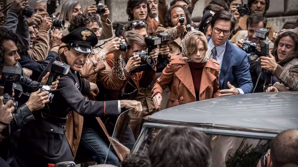 Gail Harris (Michelle Williams) and Fletcher Chase (Mark Wahlberg) push through photographers beside a car