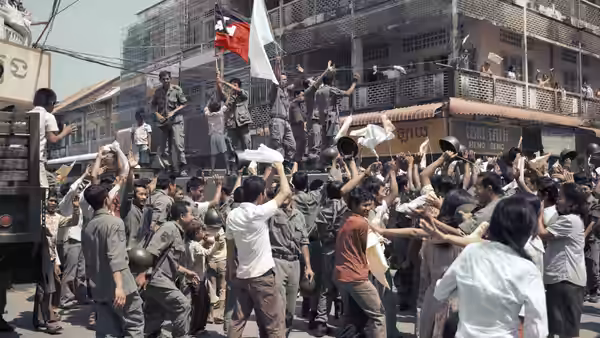 A crowd reaches toward soldiers distributing supplies in a city street
