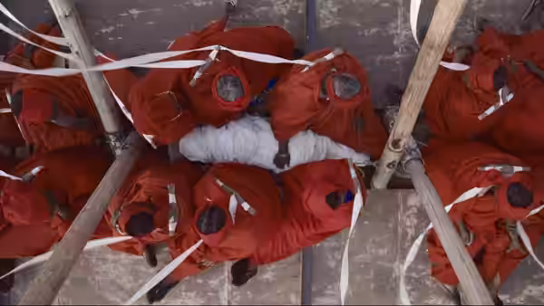 Red-clad women lie in rows, each bound by a white ribbon