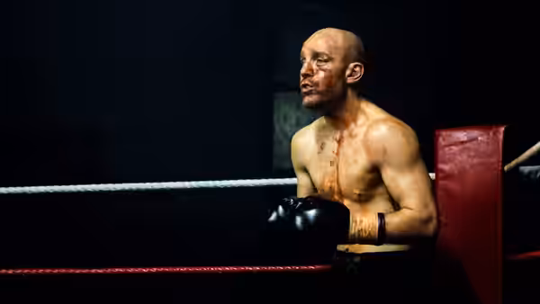 Jimmy McCabe (Johnny Harris), bruised and gloved, stands in a boxing ring