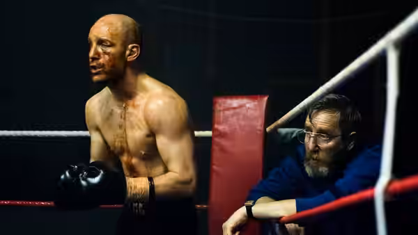 Jimmy McCabe (Johnny Harris) stands in the ring beside an older man leaning on the ropes