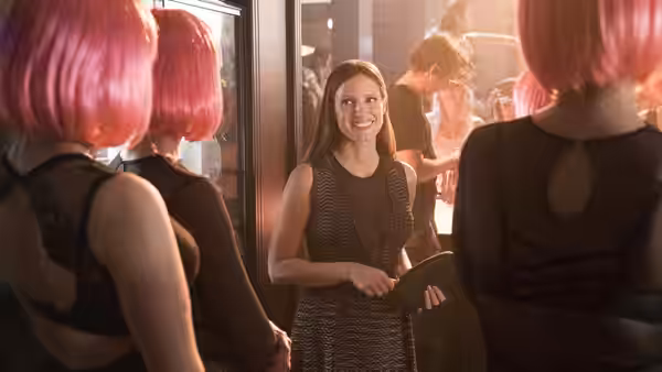 Molly Bloom (Jessica Chastain) stands among guests at a party holding a folder
