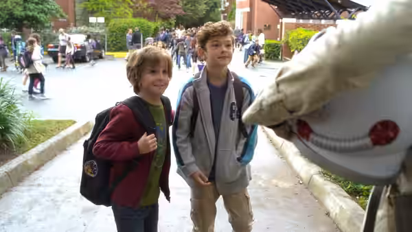 Auggie (Jacob Tremblay) and Jack Will (Noah Jupe) greet a helmeted astronaut outdoors