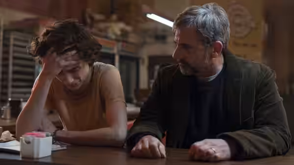 Nic Sheff leans on a table as David sits beside him in a shop