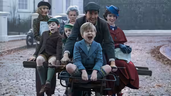 Mary Poppins and Jack ride a wheeled cart with the Banks children through a snowy London street