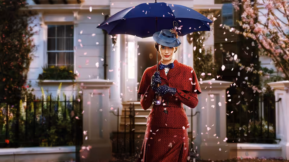 Mary Poppins (Emily Blunt) stands beneath her umbrella outside a London townhouse as petals swirl around her