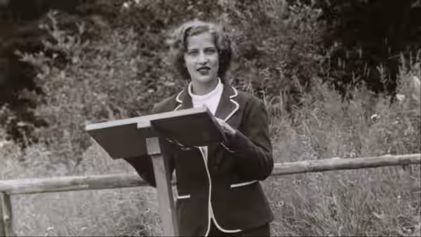 Young Ruth Bader Ginsburg (Ruth Bader Ginsburg) speaks at a lectern outdoors in archival footage