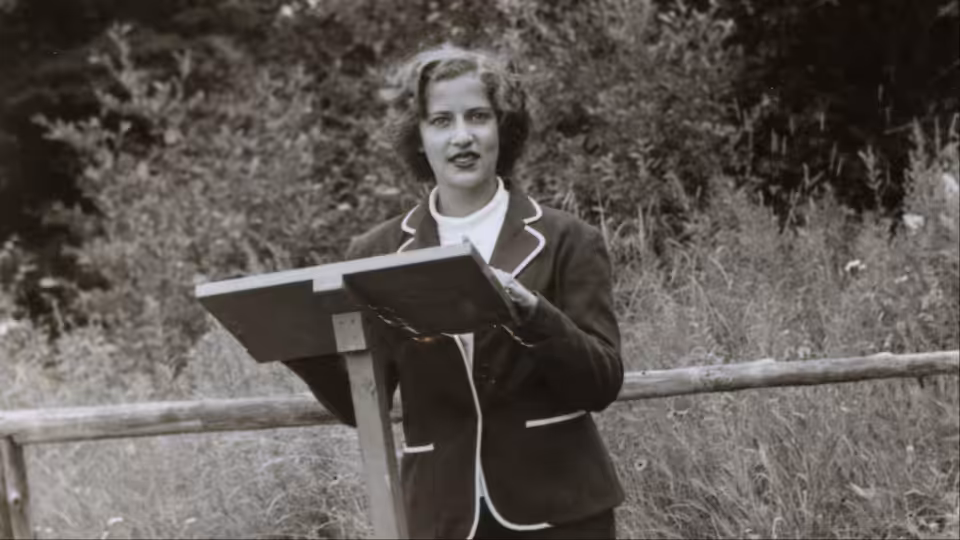 Young Ruth Bader Ginsburg (Ruth Bader Ginsburg) speaks at a lectern outdoors in archival footage
