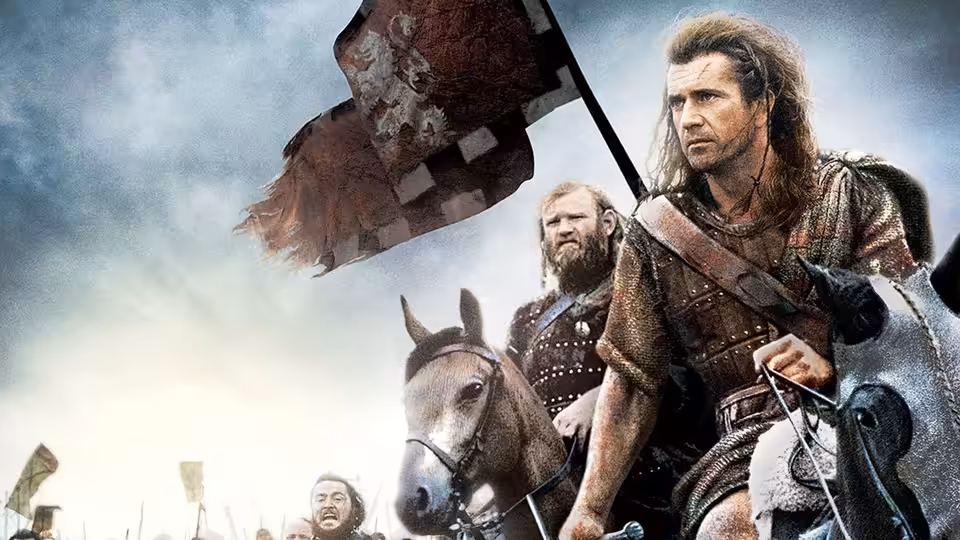 William Wallace (Mel Gibson) riding a horse while holding a tattered flag