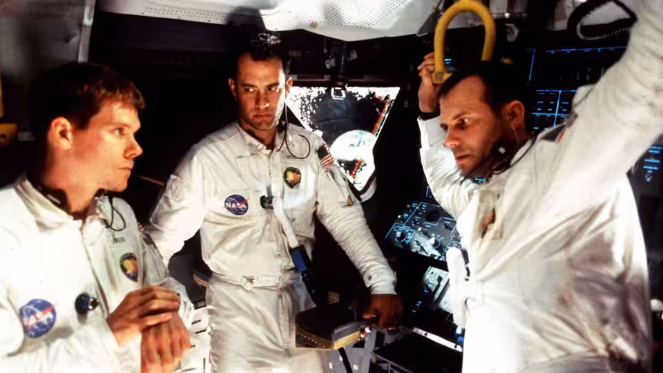 Three astronauts in white suits inside the spacecraft cabin