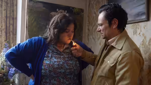 Ray (Justin Salinger) lights Liz's (Ella Smith) cigarette in a wallpapered room