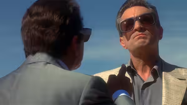 Sam 'Ace' Rothstein (Robert De Niro) in sunglasses talking to another suited man outdoors
