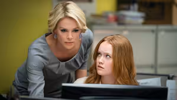 Megyn Kelly (Charlize Theron) leans over Kayla Pospisil (Margot Robbie) at a computer