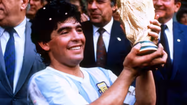 Diego Maradona lifts the World Cup trophy while wearing Argentina's striped jersey