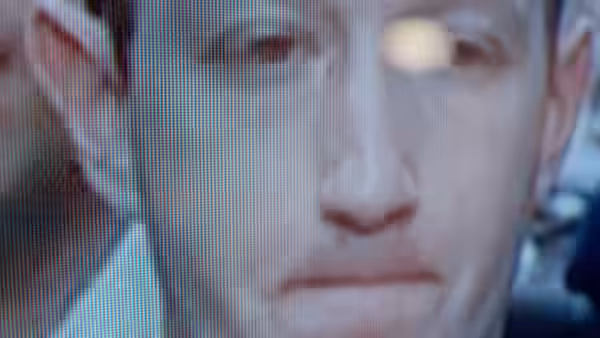 A close-up of a man’s face fills a pixelated screen