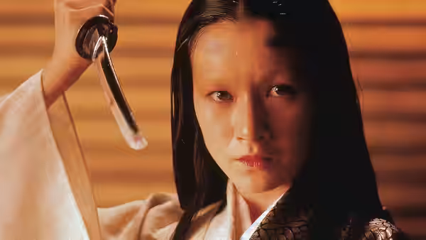 Woman in white kimono raising a sword near her face