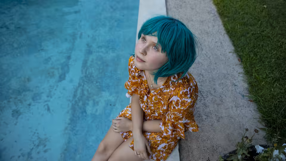Milla (Eliza Scanlen) sits beside a swimming pool, looking upward