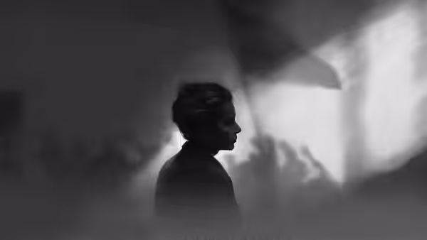 A woman stands in profile as shadows and light fall across a wall