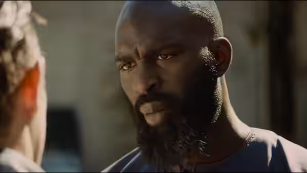 A bald, bearded man confronts someone at close range