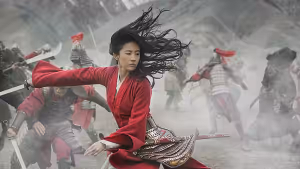 Hua Mulan (Liu Yifei) fights red-armored soldiers amid swirling dust