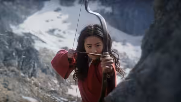 Hua Mulan (Liu Yifei) draws her bow among snowy mountain cliffs